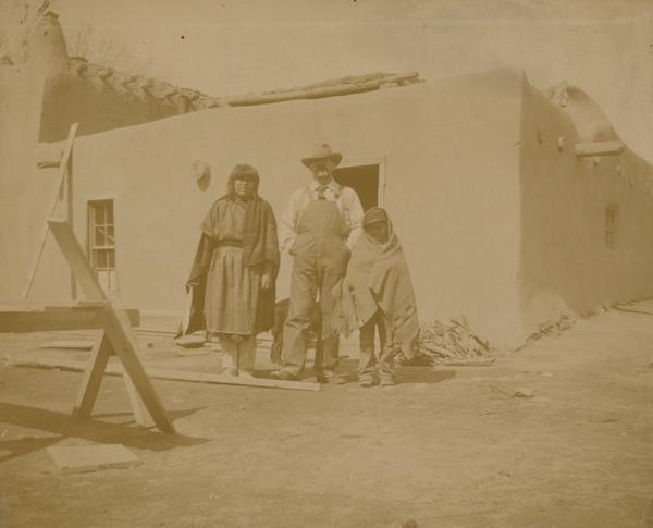A San Ildefonso Pueblo family stands in front of a building.