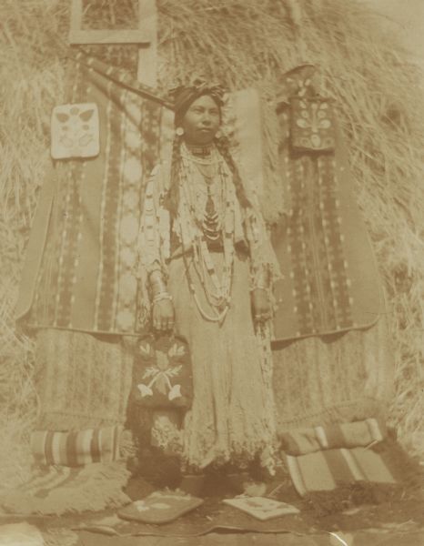 Charlotte Edwards, an Indian girl, wears a buckskin dress with beads and bracelets on each wrist at the Warm Springs Agency in Oregon.