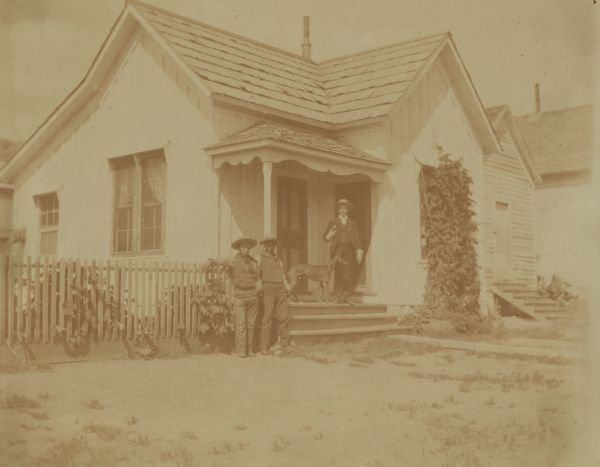 The physician's residence, with the office just beyond, at the Warm Springs Agency in Oregon.  Three men and a dog gather at the porch.
