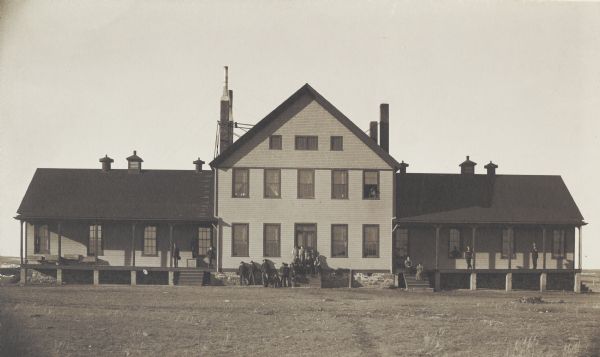 The Blackfeet Agency Hospital in Browning, Montana.  People gather near the front door and on the porches.