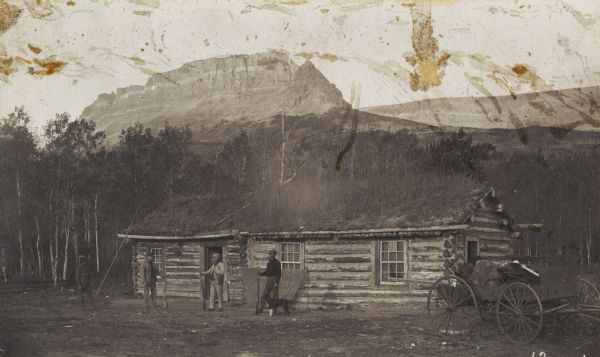 Norris' flat at Upper St. Mary's Lake, with men standing in front of the cabin.