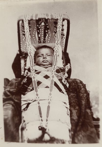 An Osage infant is wrapped in a cradle. This image comes from an Osage album with the inscription: "Compliments of G.W. Parsons."
