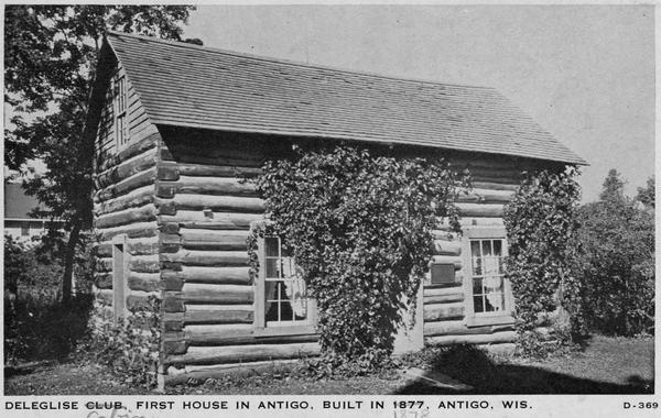 The first house in Antigo, the Deleglise cabin, built in 1878. Caption reads: "Deleglise Club, First House in Antigo, Built in 1877, Antigo, Wis." Handwriting on caption crossed out "Club" and added "Cabin", and "1877" is also crossed out and "1878" was added.