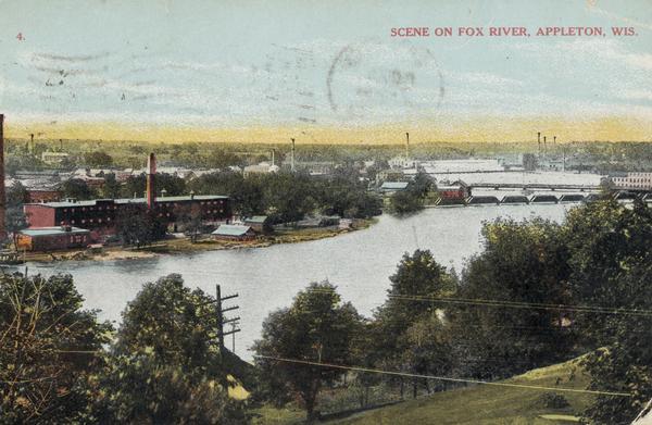 View from hill looking down towards the Fox River. On the opposite shoreline are industrial buildings. Further down the river on the right are bridges. Caption reads: "Scene On Fox River, Appleton, Wis."