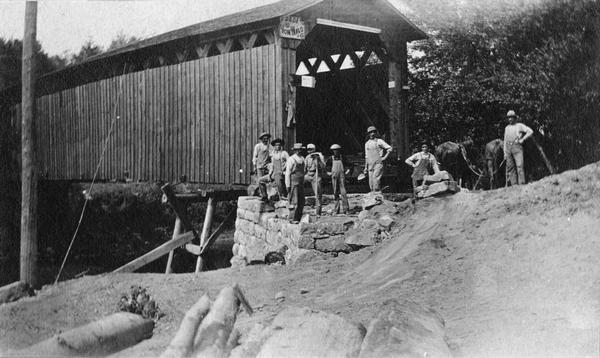 Construction workers stand in front of the Butterfield covered bridge.