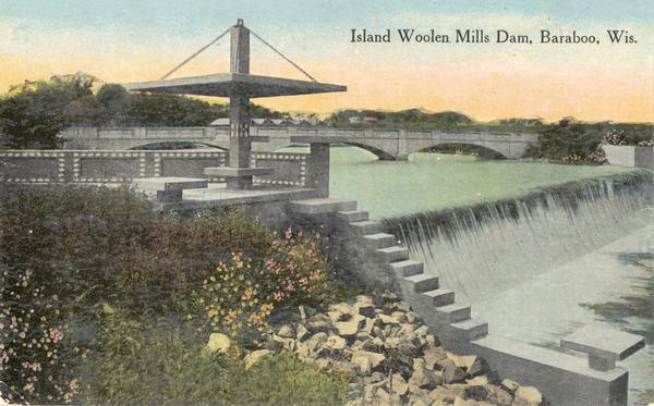 Slightly elevated view of the dam, with a bridge in the background. Caption reads: "Island Wollen Mills Dam, Baraboo, Wis."