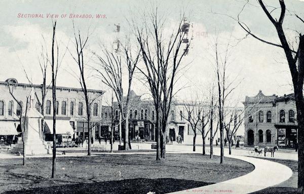 Downtown view of Baraboo featuring multiple buildings around the square, a monument, and a horse and buggy. Caption reads: "Sectional View of Baraboo, Wis."
