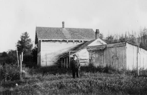 Back view of the E. Pike residence. A man is standing in the center. The owner is thought to have been a relative of Robinson D. Pike (1838-1905), a lumber merchant and the founder of Bayfield.