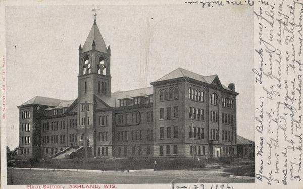 Front view of the four story high school with a tower above the the entrance. Caption reads: "High School, Ashland, Wis."