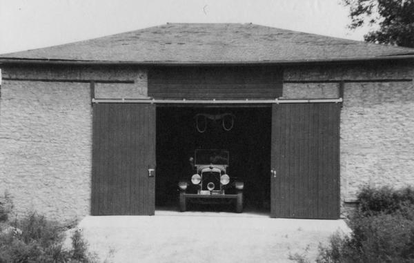 View of a car in the open doorway of a barn at the Bartlett Memorial Historical Museum.