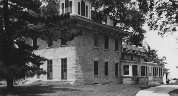 Exterior of the museum, with a pine tree to the left, partially obstructing the building, and a path to the right.