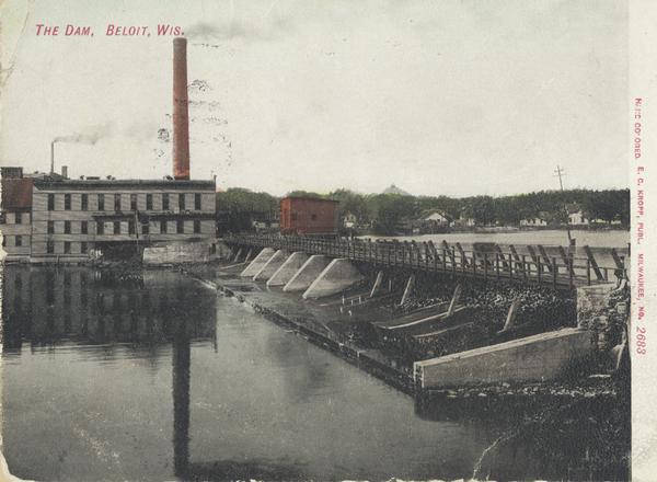 View of the dam and power plant over the river, with smokestacks in the background. Caption reads: "The Dam, Beloit, Wis."