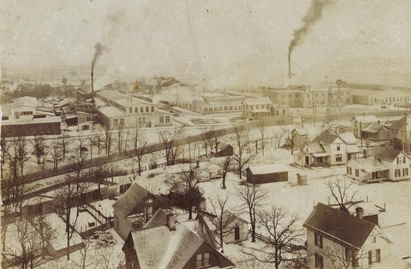 Elevated winter view of the company buildings and residential area, with smokestacks in the background.