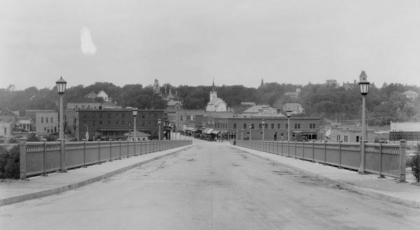 View of bridge over Black River Falls, looking at downtown buildings.