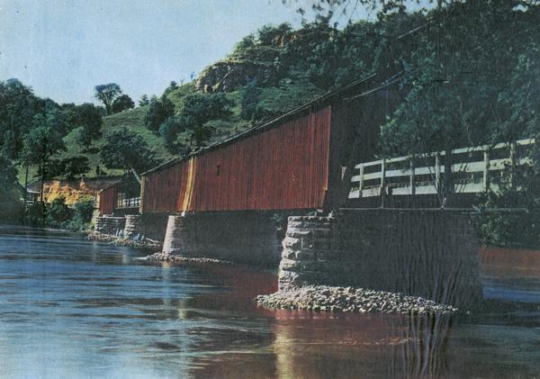 View of covered bridge, built in 1890, over the Wisconsin River with surrounding landscape.