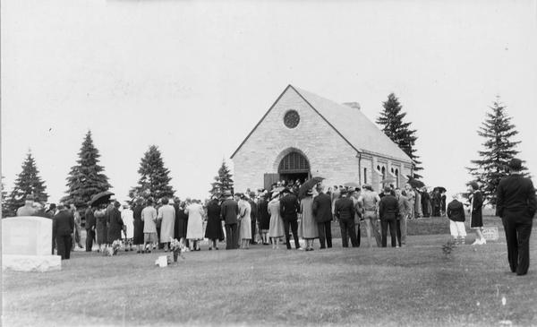 View of Memorial Chapel, dedicated on May 8, 1939. A group of people are gathered on the lawn in front of the chapel.