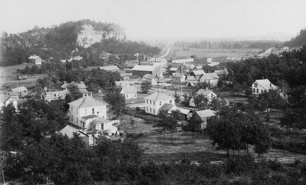 Elevated view of Camp Williams Town, with many houses. In the background are bluffs.
