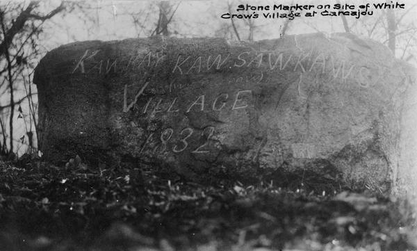 Close-up view of an etched stone that says, "Kaw Kay Kawsawkaws (White Crow) Village 1832."