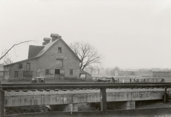 View towards a barn, with a railroad bridge in the foreground.