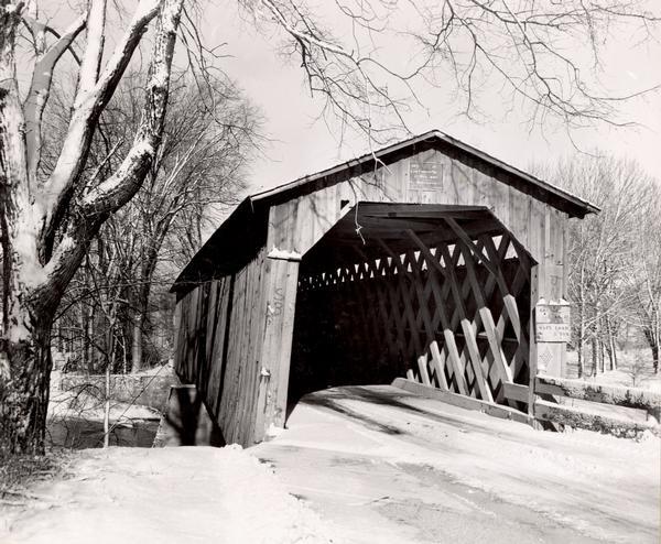 Covered bridge over Cedar Creek in Ozaukee County on highway, about one mile north of Cedarburg. The last remaining covered bridge in Wisconsin. Snow is on the ground.