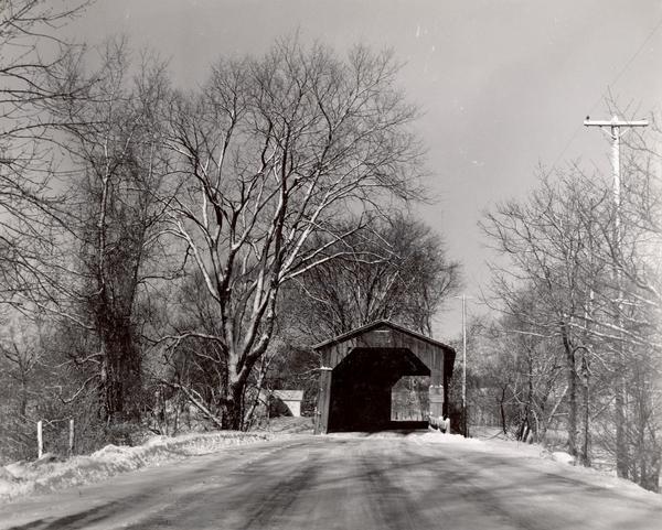 Covered bridge over Cedar Creek in Ozaukee County on highway, about one mile north of Cedarburg. The last remaining covered bridge in Wisconsin. Snow is on the ground.