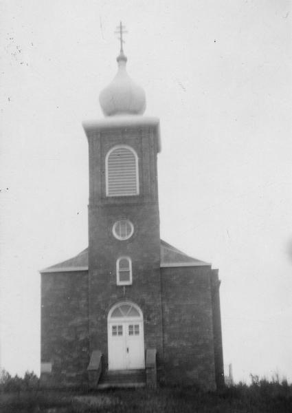 View towards the front of a Russian church, with a triple cross on top of the onion dome.