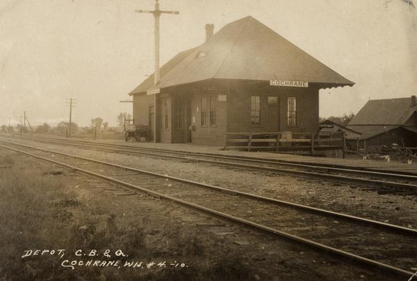 Railroad depot with two sets of railroad tracks in the foreground.