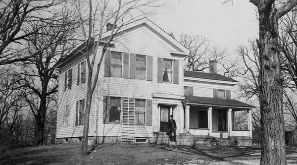 Governor Taylor's farm home. The man standing on the porch is John Killian, owner of the farm when the photograph was taken.