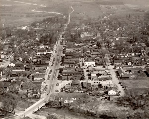 Aerial view of main street. There is a bridge with a stream flowing under it in the foreground.