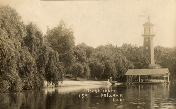 View of the north shore of Delavan Lake with a lighthouse in the background. Also known as "Red Top" and "L.P. Sutter's." Caption reads: North Shore, Delavan Lake".