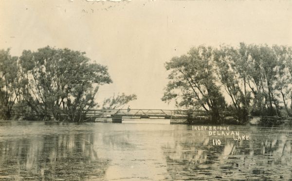 View across water towards the Inlet Bridge on Delavan Lake. Caption reads: "Inlet Bridge, Delavan Lake".
