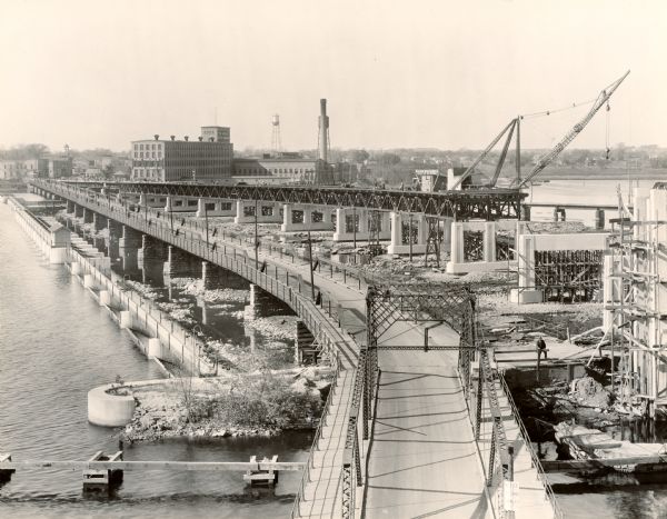 Elevated view of the bridge over a river. The Nicolet Paper Company is at the end of the bridge on the far shoreline.