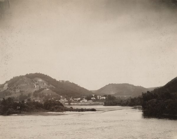 River with distant hills behind a town. An island is in the foreground.