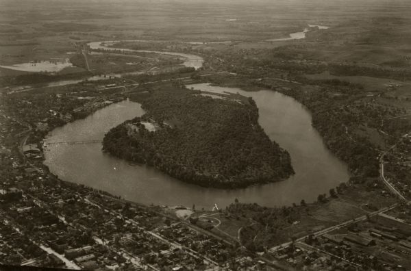 Aerial view of Carson Park, Half Moon Lake and part of the West Side in the foreground. The municipal bath house is on the lake shore in the foreground. A long section of the Chippewa River is in the distance, with the Milwaukee Railroad Bridge and Shawtown wagon bridge.