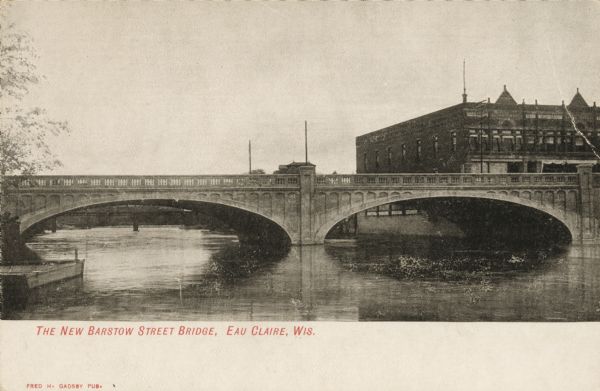 View of the bridge and brick building. Caption reads: "The New Barstow Street Bridge, Eau Claire, Wis."