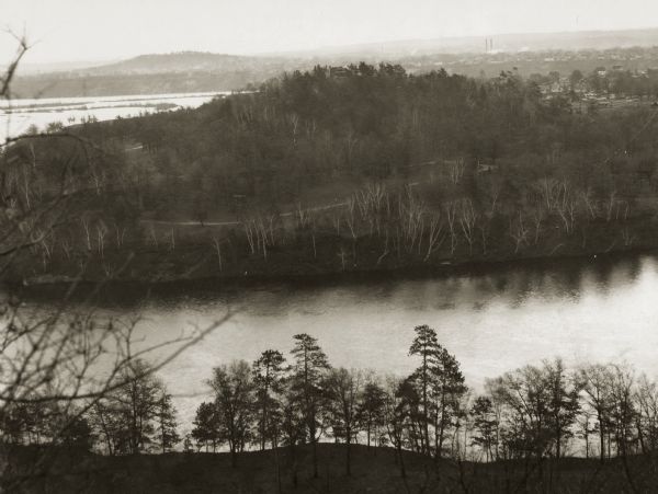 Elevated view of the "mount" and the wide river before it and behind it. Houses and smokestacks can be seen in the far distance.