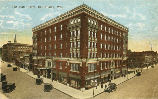 Elevated view of the hotel, with several cars parked on both sides of the hotel, and pedestrians strolling on the sidewalks. Caption reads: "The Eau Claire, Eau Claire, Wis."
