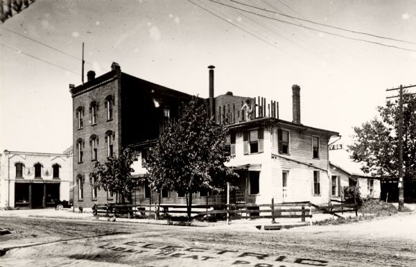Tearing down Eau Claire House to make way for the Y.M.C.A. building. A man is standing on the roof. A sign in the street reads, in part: "Electric Light Heat Po[wer]".