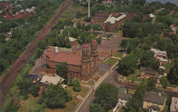 Aerial view of the church (built in 1928), the rectory (built in 1876), the school (built in 1958), and the convent (built in 1941).  Also includes a view of the Sacred Heart Hospital.