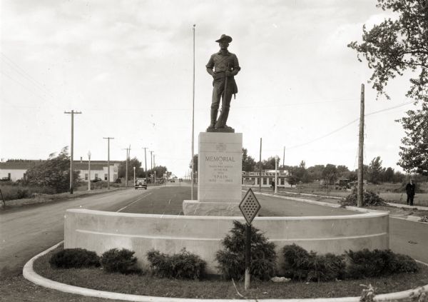 View of a boulevard containing a Spanish war memorial statue. The plaque on the statue's base reads: "Memorial to those who served in the war with Spain, 1898 - 1902."