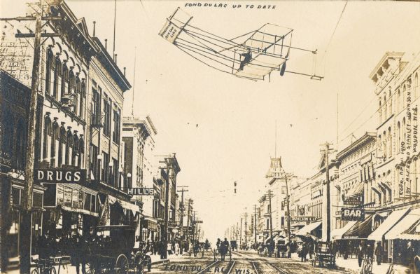 Street scene in Fond du Lac featuring many pedestrians, horse-drawn carriages, shops, and other buildings. Caption reads: "Fond du Lac Up To Date". An image of a plane has been added to the sky.