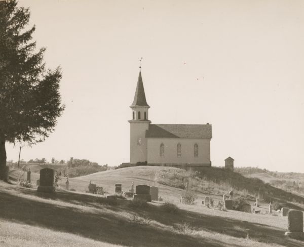 View of a rural church on a hill and its adjacent cemetery. Beaver Creek Lutheran Church was or still is a Norwegian church.