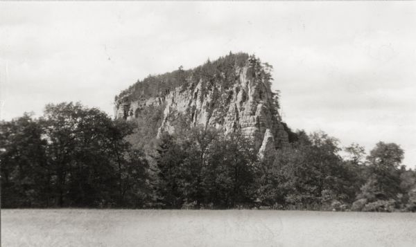View of a large geological rock formation at the base of a river or lake.