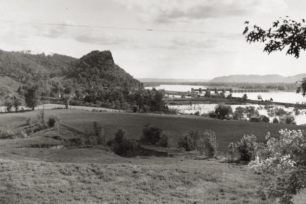 View across fields towards the Genoa Dam on the Mississippi River. Tree-covered hills are on the left.