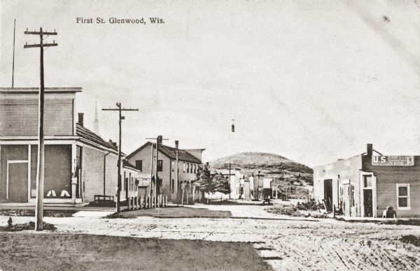 View down street in downtown Glenwood, Wisconsin. Caption reads: "First St. Glenwood, Wis."
