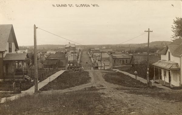 Looking down unpaved North Grand street, which appears to be the main street of Glidden, Wisconsin. Caption reads: "N. Grand St. Glidden Wis."