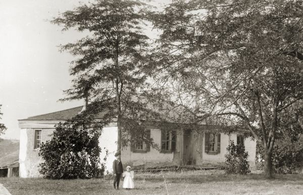 View of Governor James Duane Doty's home with two children standing in front. The Doty home was the first brick house in Wisconsin. The materials were transported from Detroit by boat.