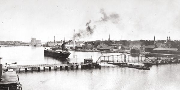 Slightly elevated view of the Fox River, with a bridge and ship in the river.