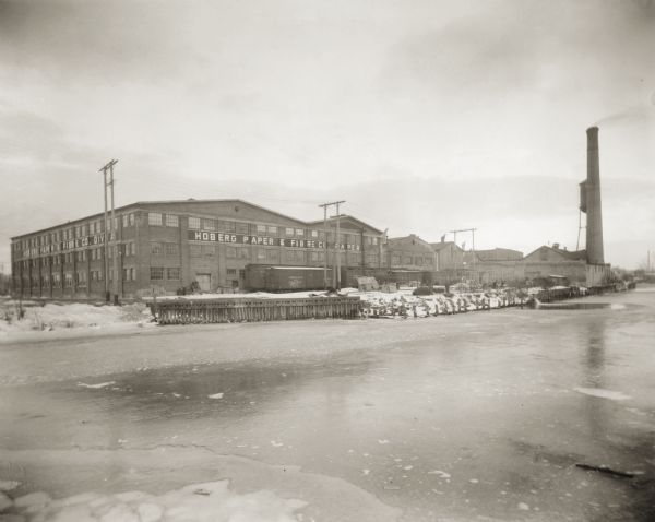 Hoberg Paper and Fibre Company buildings along the East River. Ice is on the river in the foreground.