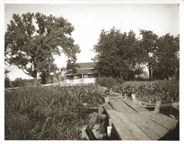 View of the Tank cottage on its original site on the west side of the Fox River. The cottage was built in 1776 by Joseph Roi, a fur trader, who lived in it until 1805 when it was purchased by Jacques Porlier. Later, the Tank family, who presented Tank Park to the city, lived in it.  In 1908, the cottage was moved one mile north to Union Park (minus one wing which collapsed during the move).